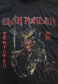 Sort t-shirt med et grafik af en samurai-figur med røde øjne, der holder et sværd. "IRON MAIDEN" tekst i rød vises ovenpå.