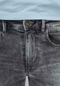 Grå denimjeans med en blekt finish, med en kopparknapp i midjan, fem fickor och subtila sömdetaljer.