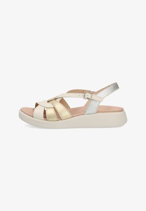 Sandalias con una base blanca, tiras metálicas doradas y plateadas, diseño de punta abierta y suela de plataforma acolchada para mayor comodidad.