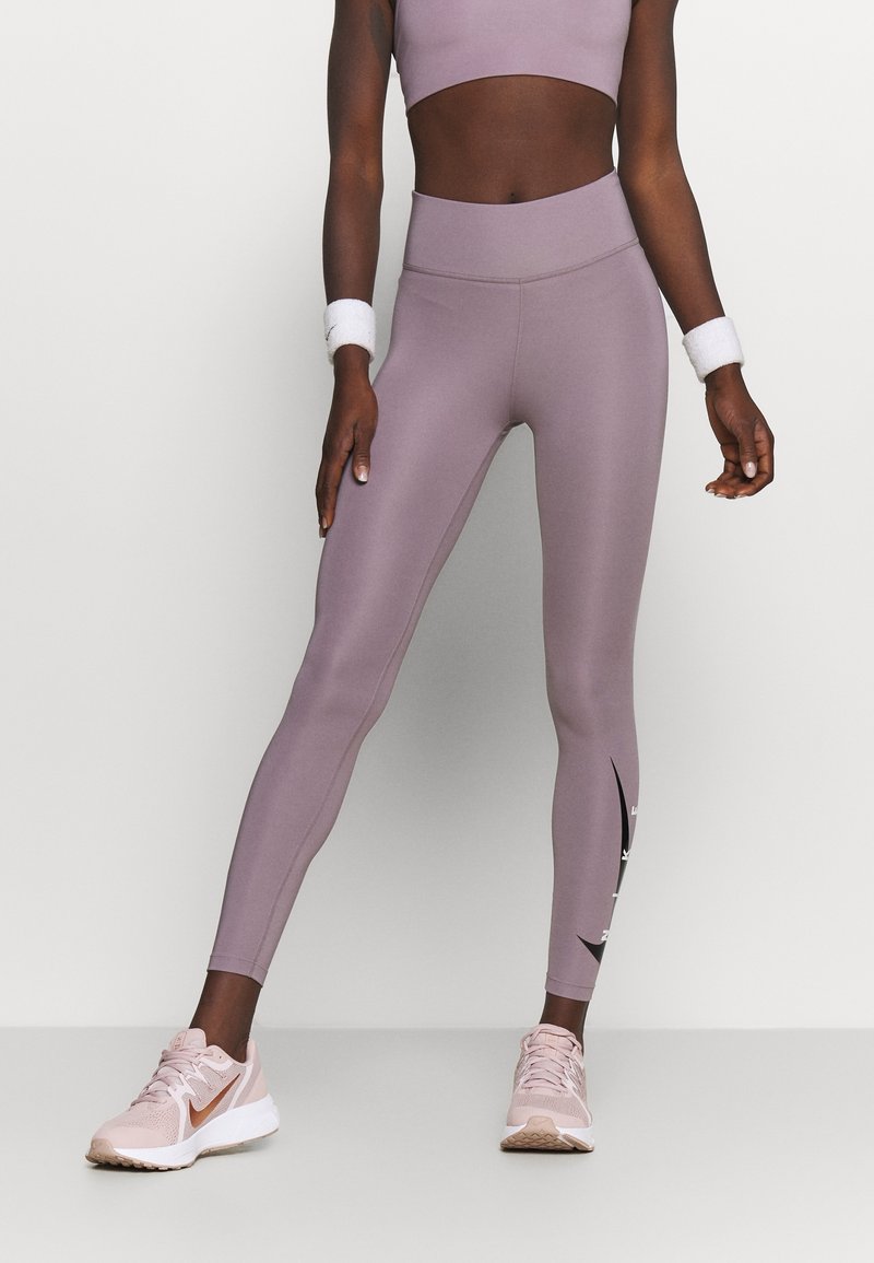 Leggings taille haute lilas en tissu lisse, avec des accents sur les côtés et un détail de logo. Assortis à des chaussures de sport rose clair.
