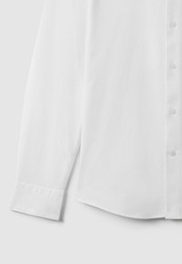 Cămașă albă cu nasturi, fabricată dintr-un material din bumbac fin, cu mâneci lungi și manșete cu nasturi, și un design elegant al gulerului.