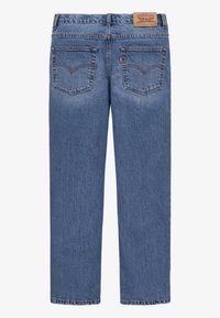 Jean en denim bleu à coupe droite vu de dos avec deux poches arrière, passants de ceinture et un patch de marque en cuir marron sur la ceinture.