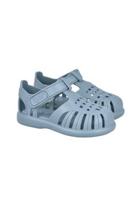 Sandalias de plástico azules con punta cerrada, lados abiertos, correa ajustable y patrones recortados para ventilación. Suela texturizada para un mejor agarre.
