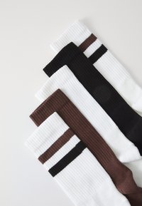 Four pairs of socks: two white with black and brown stripes, one brown, and one black. Ribbed texture, varied colors and designs.
