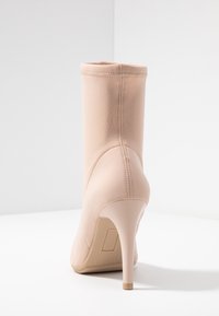 Nude botki za kostkę o gładkim, dopasowanym fasonie, gładkiej teksturze, wysokim obcasie w szpilkę oraz wzmocnionym szwie na tyle.