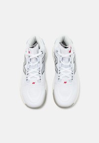 Zapatillas deportivas blancas con parte superior de malla, con acentos plateados y marca roja. Punta redondeada y suela texturizada para mayor agarre. Los cordones son blancos.