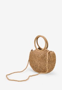 Bolso tejido redondo hecho de fibras naturales, con dos asas circulares y una correa larga trenzada, en un color marrón claro con una superficie texturizada.