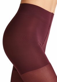 Leggings bordeaux con una texture liscia, vita alta e dettagli a coste nella parte inferiore. Design elasticizzato e aderente.