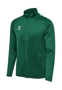 Zielona sportowa kurtka na długi rękaw z zamkiem, wysokim kołnierzem, białym logo Hummel na piersi i wzorem w jodełkę na ramionach.