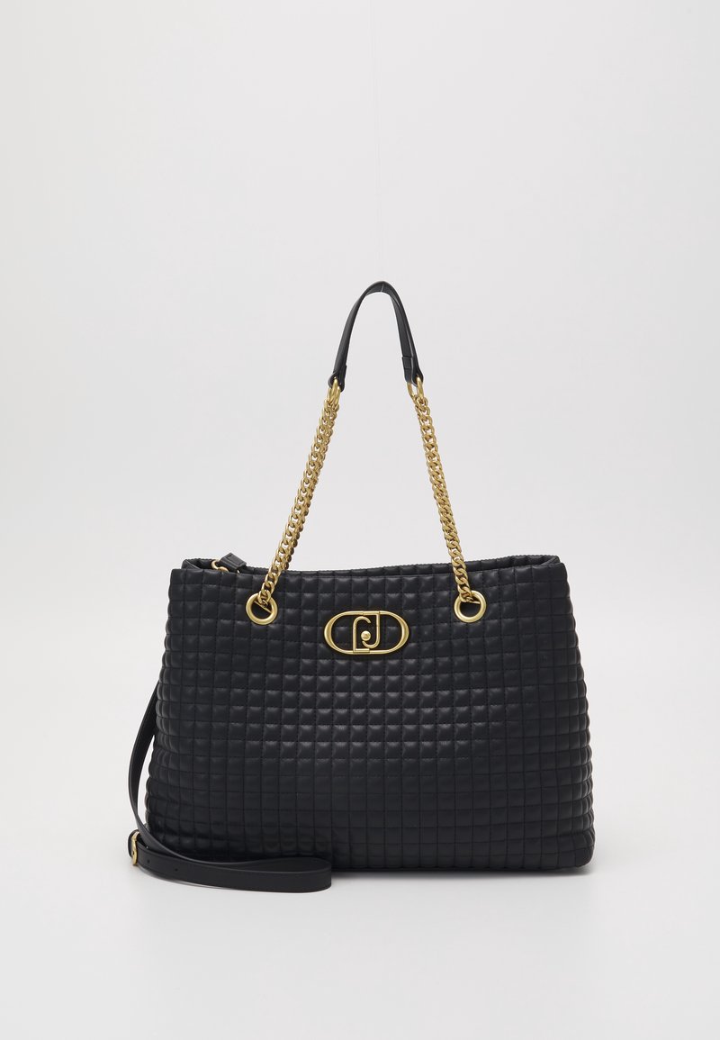 Sac à main en cuir matelassé noir avec anses en chaîne dorée et plaque ovale dorée à logo sur le devant, plus une bandoulière en cuir réglable.