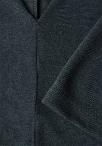 Neulepaita tummanvihreänä, jossa on V-pääntie ja lyhyet hihat. Suora pinta, jossa on hienovaraisia roiskeita ja siistit ompeluyksityiskohdat.