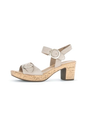 Beige suede heeled sandals with adjustable ankle strap, round buckle detail, and textured cork platform. Chunky block heel design.