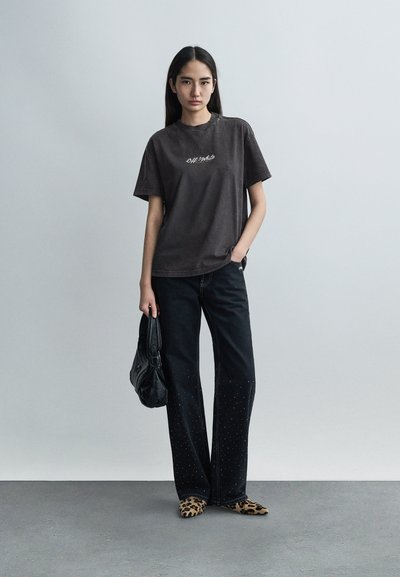 Μαύρο βαμβακερό T-shirt με λογότυπο, συνδυασμένο με μαύρο ευρύχωρο τζιν παντελόνι με διακοσμητικές καρφίτσες. Ολοκληρώνεται με μαύρη τσάντα και παπούτσια με λεοπάρ μοτίβο.