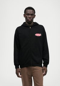 Black zip-up hoodie with a front pocket and a red logo design on the left chest. Cotton material with a relaxed fit and hood.