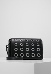 Bolso bandolera de cuero negro con ojales circulares plateados en patrón de cuadrícula, con correa desmontable y acabado mate y suave.