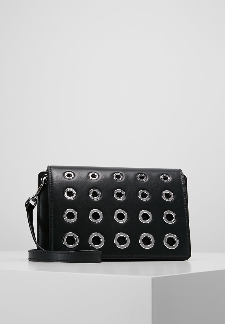 Bolso bandolera de cuero negro con ojales circulares plateados en patrón de cuadrícula, con correa desmontable y acabado mate y suave.