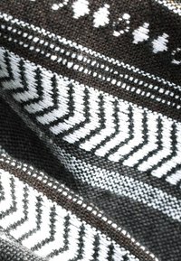Tissu tissé noir et blanc avec motifs géométriques en zigzag et en pointillés en bandes horizontales.