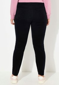 Svarta kordflorsbyxor med slim fit, med två bakfickor och slät yta. Stylerade med en rosa långärmad topp och plattformssneakers.