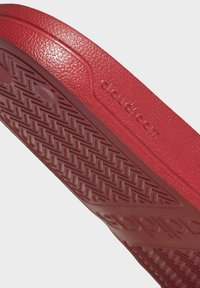 Röd gummisul med texturerad yta, som har ett zigzag-mönster och präglad "cloudfoam"-logotyp på sidan.