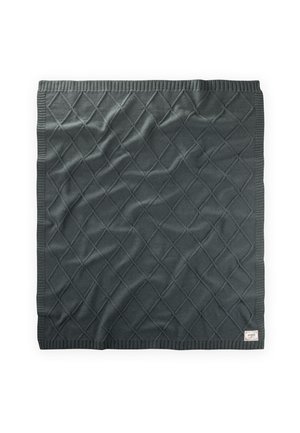 Couverture en tricot gris foncé avec motif en losange et bords côtelés, pliée à plat avec une petite étiquette en tissu dans le coin inférieur droit.