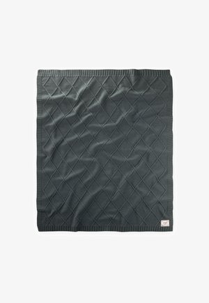 Couverture en tricot gris foncé avec motif en losange et bords côtelés, pliée à plat avec une petite étiquette en tissu dans le coin inférieur droit.