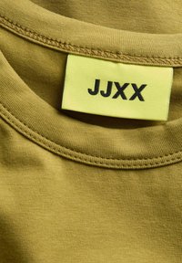 Olivově zelené bavlněné tričko s žebrovaným kulatým výstřihem a žlutou cedulkou s nápisem "JJXX" v černém písmu. Textura je hladká a přiléhavá.