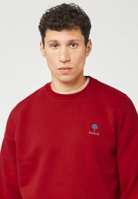 Bordeaux sweatshirt met een geribbelde ronde halslijn, geborduurd blauw boompje logo op de linkerborst en een textuurstof. Lichtgewicht en casual pasvorm.