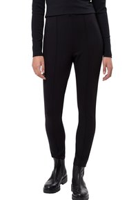 Leggings noirs taille haute en tissu extensible, avec coutures avant et jambes fuselées ; associés à des bottines noires épaisses.