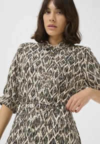 Abito button-up con un motivo geometrico crema e nero, dotato di maniche corte, colletto e dettaglio in vita franziato.