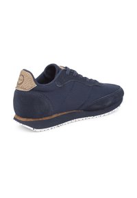 Marineblaue Sportschuhe aus Mesh- und Wildledermaterialien, mit strukturierten, tanfarbenen Akzenten an der Ferse und einer gesprenkelten weißen Sohle. Abgerundete Form.