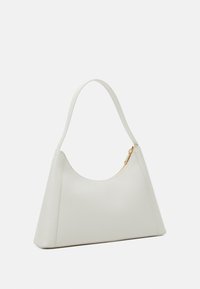 Borsa in pelle color crema di forma triangolare, con una lunga maniglia e un accentuato zip in oro. Texture liscia, design minimalista.