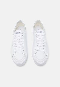 Sneaker bianchi in pelle con lacci piatti, punta rotonda e colletto imbottito. Presenta il logo Tommy Hilfiger sulla linguetta e sul lato. Suola in gomma piatta.