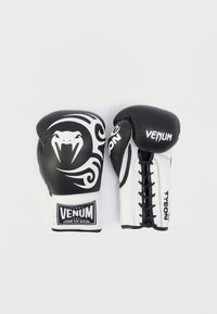Μαύρα και λευκά γάντια πυγμαχίας με σχέδιο φίδι, κλείσιμο με κορδόνια και λογότυπα των εμπορικών σημάτων "VENUM" και "TYSON" στους καρπούς.
