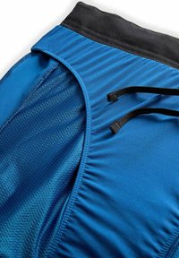 Primer plano de pantalones cortos deportivos azules con cintura y cordones negros, que cuentan con un forro interior de malla para mayor transpirabilidad.