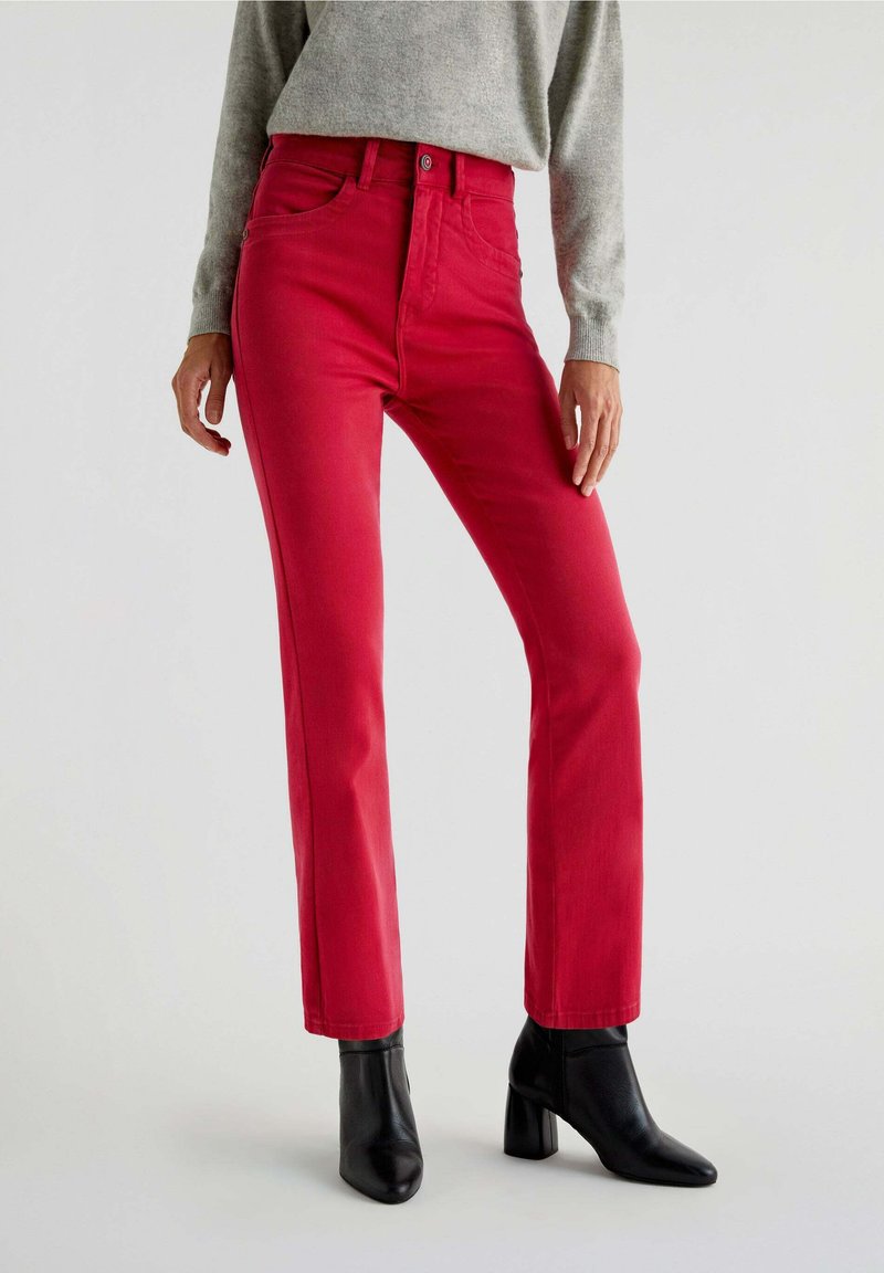 Røde denim jeans med en tætsiddende talje, lige ben og fem lommer. Båret med grå sweater og sorte hælede ankelstøvler.