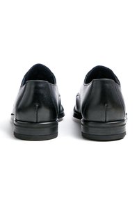 Zwarte leren schoenen met een gladde afwerking, een afgeronde neus, lage hak en subtiele stiksel details aan de achterkant. Minimalistisch ontwerp.