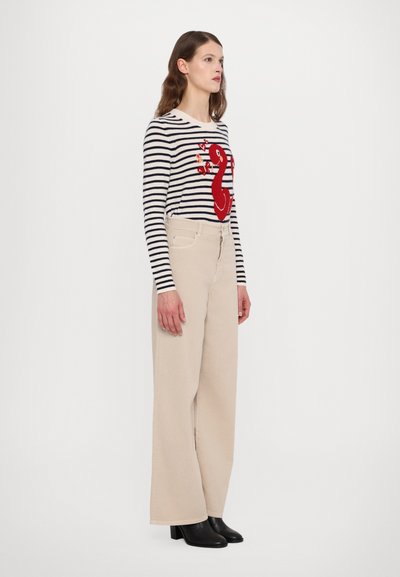 Gestreepte lange mouwen shirt met rode geborduurde zwaanontwerp, gecombineerd met beige wijde broek en zwarte hak enkellaarsjes.