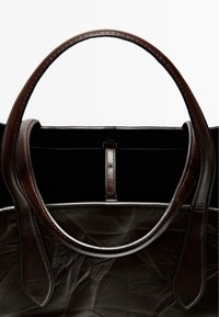Brun läder tote-väska med en slät, texturerad yta, med korta handtag och en minimalistisk design. Inuti är den svart.
