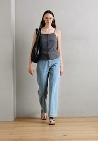 Gray fitted cropped top with thin straps, light blue straight-leg jeans, black oversized handbag, and brown sandals with straps.