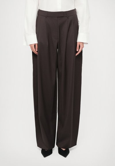 Pantalons à jambes larges en tissu marron foncé avec une texture lisse, dotés de plis frontaux, d'une taille cintrée et de poches latérales.