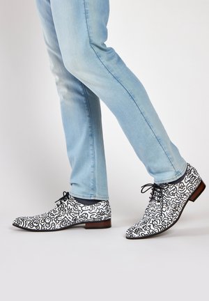 Zwart-witte gestreepte leren veterschoenen met een spitse neus, gecombineerd met lichtblauwe spijkerbroeken.