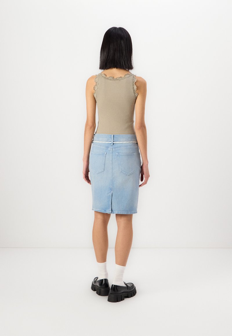 Hellbeige, geripptes Tanktop mit gewellten Kanten, kombiniert mit einem mittel-langen, hellblauen Jeansrock mit Gesäßtaschen und einem Reißverschluss.