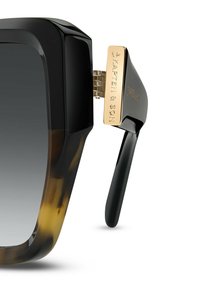 Yli suuria aurinkolaseja, joissa on kiiltävä musta ja kilpikonnakuorosarja, gradienttilinssit ja kultaiset metallikorostukset temppeleissä.