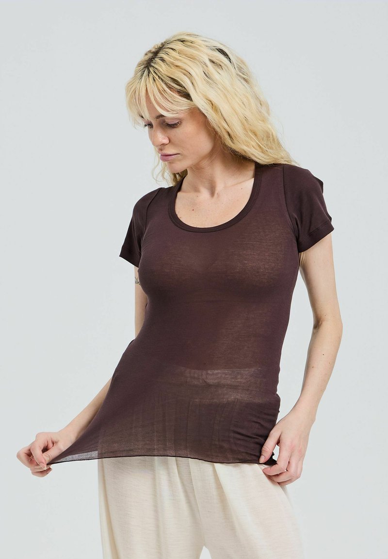 Brun, åtsittande T-shirt med korta ärmar och rund halsringning, med en mjuk, genomskinlig textur. Matchad med lätta, lösa byxor.