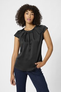 Blouse en satin noir à manches courtes, avec un col plissé et un ourlet arrondi. Associée à un jean bleu foncé, mettant en avant une texture lisse et brillante.