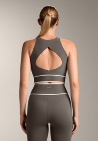 Gray athletic crop top with a cutout back, featuring contrasting white bands at the hem. The fabric appears stretchy and smooth.