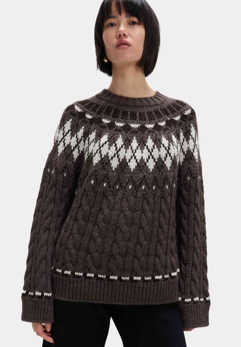 Maglione marrone a maglia con colletto rotondo, caratterizzato da motivi a rombi bianchi sulla spalla e con polsini e orlo a coste.