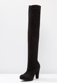 Black over-the-knee boot made of soft suede with a chunky high heel and rounded toe, featuring a seamless design and smooth texture.