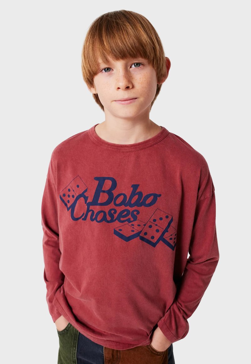 Camisa de manga larga roja con un gráfico en azul marino que presenta el texto "Bobo Choses" y dominós. Tejido suave con un corte relajado y escote redondo.