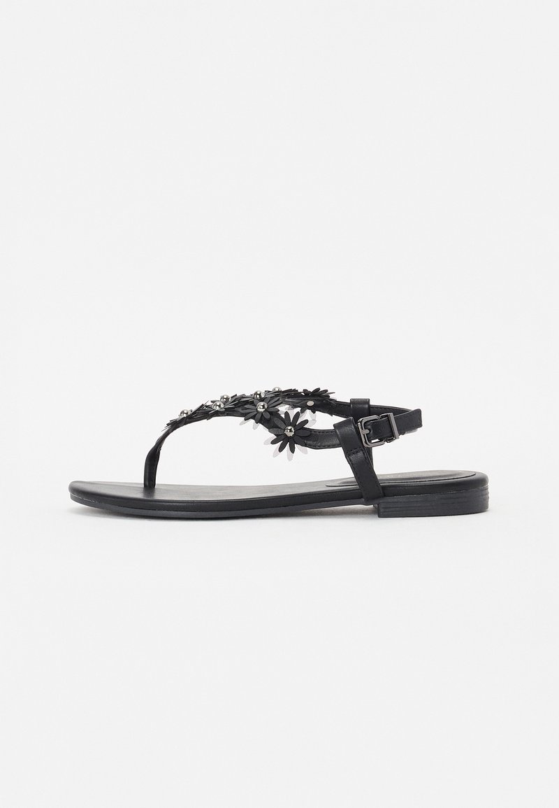 Musta sandaali, jossa on litteä pohja ja thong-muotoilu. Koristeltu kukkakuvioilla ja metallisilla yksityiskohdilla. Säädettävä solkivarsi.